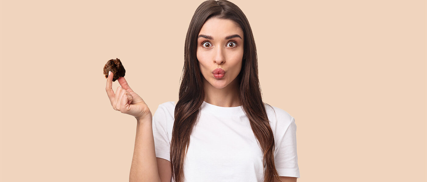 Waist-up portrait of funny and cute, adorable young woman holding two desserts macarons over eyes and smiling, playing with food, fool around, standing upbeat over white background.