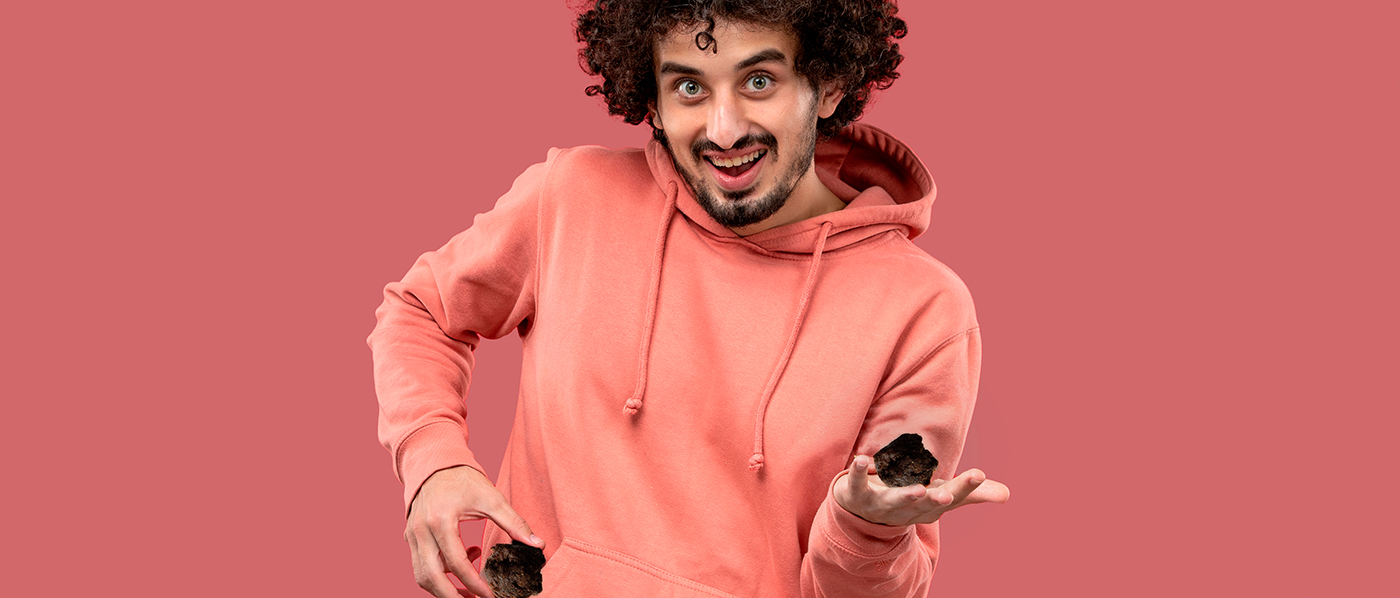 Close up shot of cheerful curly haired woman keeps mouth widely opened bites delicious macaroon enjoys eating sweet food has sugary addiction isolated over pink background. Confectionery concept